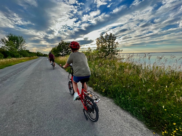 a young person wearing a helmet bikes along a road beside a body of water